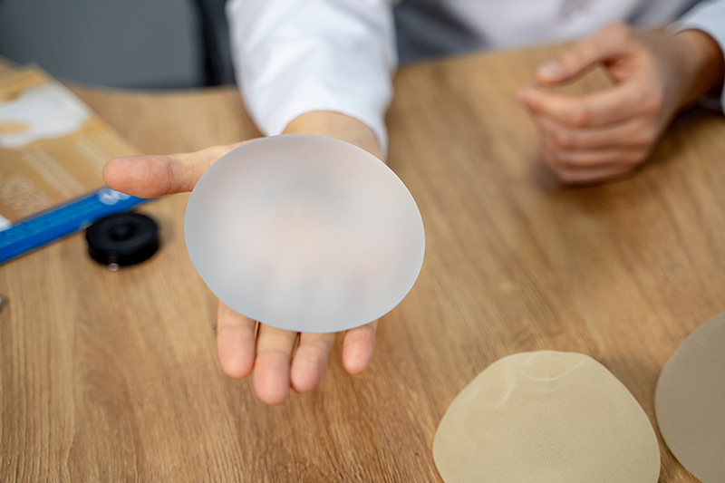 Doctor holding a round breast implant during a breast augmentation consultation